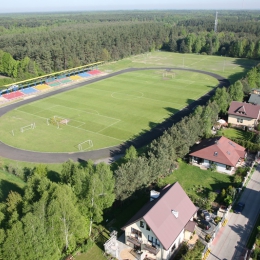 Stadion z bocznym boiskiem w tle.