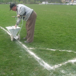 Pan Staszek przykłada się do malowania linii boiska.